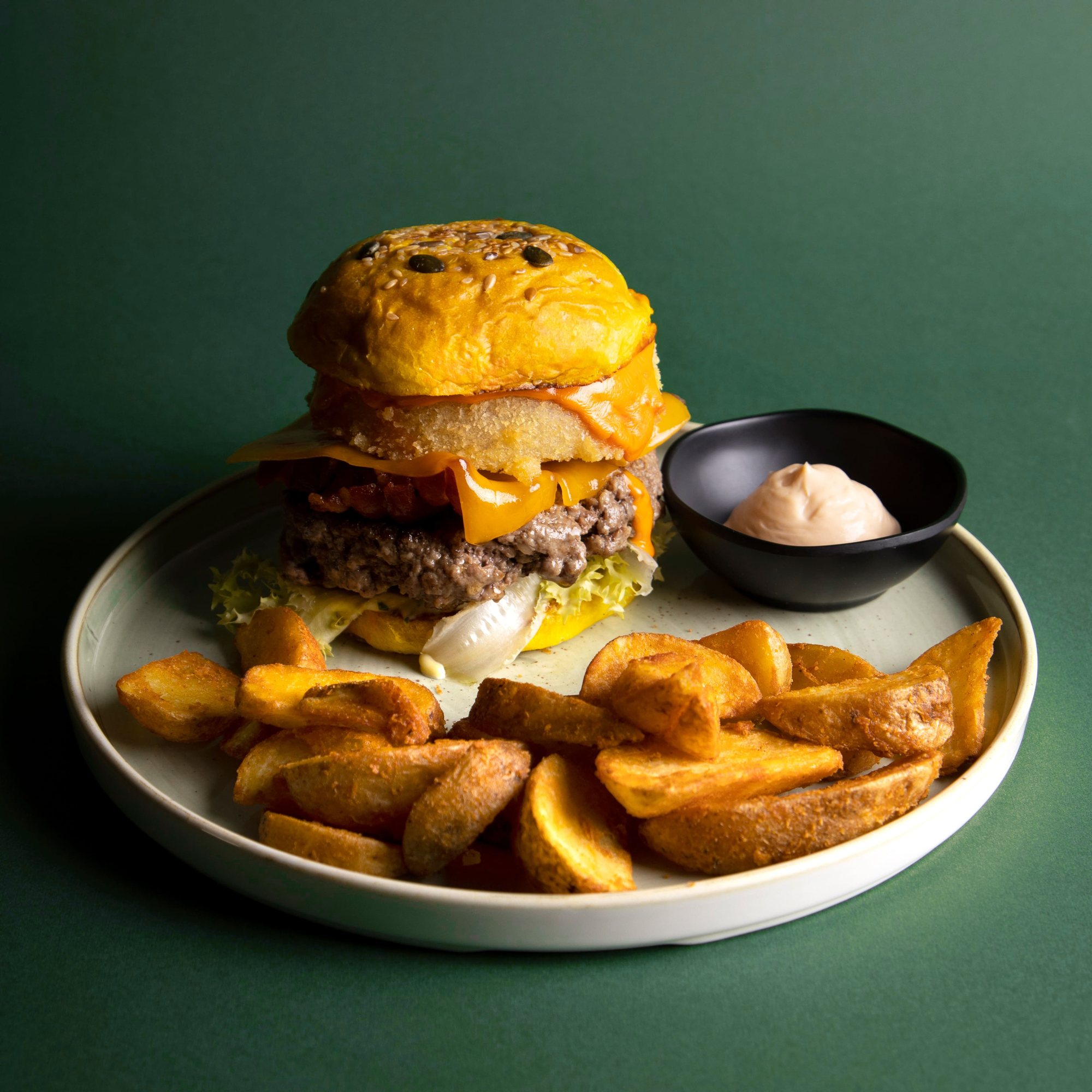 Burger con bun giallo e cheddar fuso, con patate a spicchi e salsa